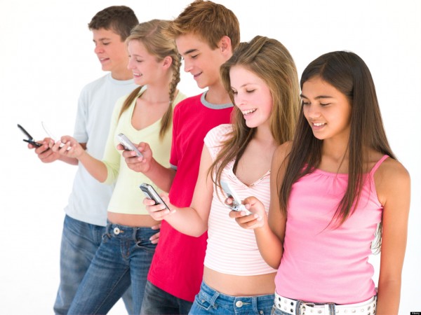 Row of five friends using cellular phones smiling