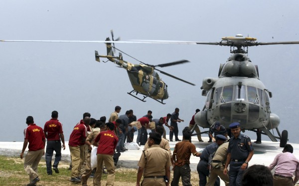 Handout of personnel from the Indian armed forces carrying relief supplies from a helicopter for stranded people at Guptkashi after heavy rains in the Himalayan state of Uttarakhand