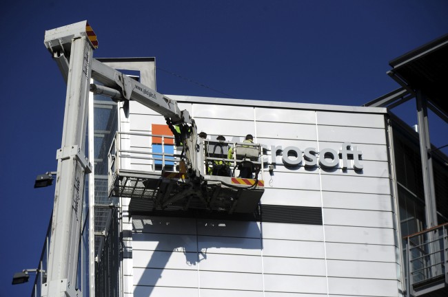 Workers install the logo of U.S. technology giant Microsoft on the wall of Nokia's former headquarters in Espoo