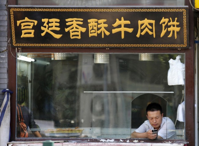A man uses a smartphone at a food stall in Beijing