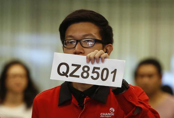 A Changi Airport staff holds up a sign to direct possible next-of-kins of passengers of AirAsia flight QZ 8501 from Indonesian city of Surabaya to Singapore, at Changi Airport in Singapore