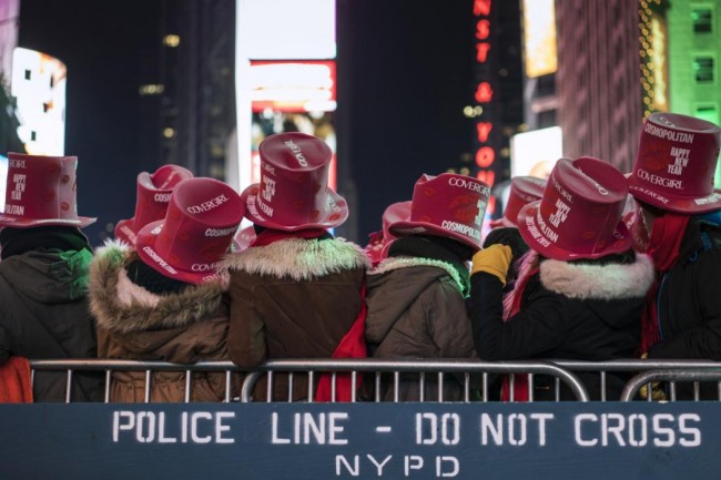 Revellers stand near a New York Police Department (NYPD) police cordon during New Year's Eve celebrations in Times Square, New York