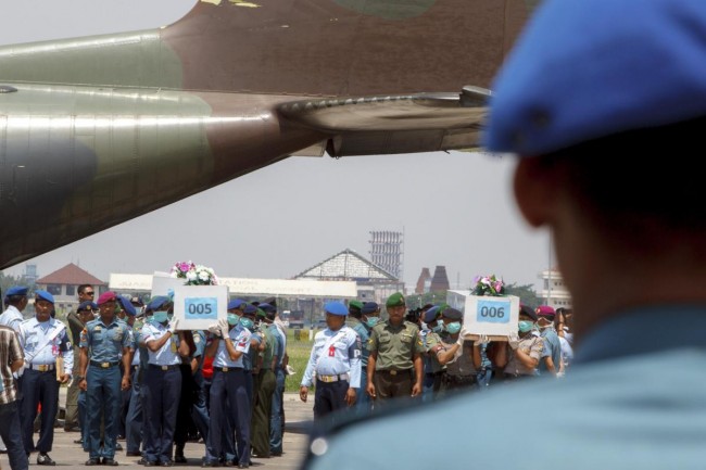 Indonesian military personnel carry caskets containing the bodies of AirAsia flight QZ8501 passengers at a military base in Surabaya