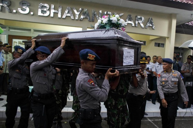 Indonesian police officers carry the coffin of AirAsia QZ8501 passenger Hayati Lutfiah at Bhayankara Hospital in Surabaya