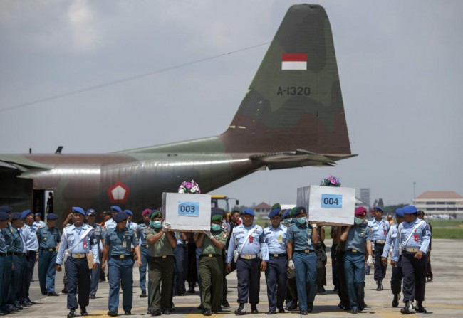 Indonesian military personnel carry caskets containing the remains of passengers onboard AirAsia flight QZ8501 at a military base in Surabaya