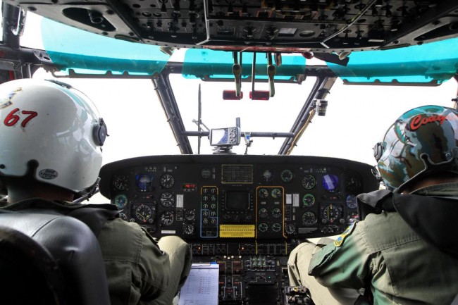 Indonesian Air Force pilots look from the cockpit windows of the Super Puma NAS 332 helicopter during a search and rescue operation over Kumai Bay in Indonesia