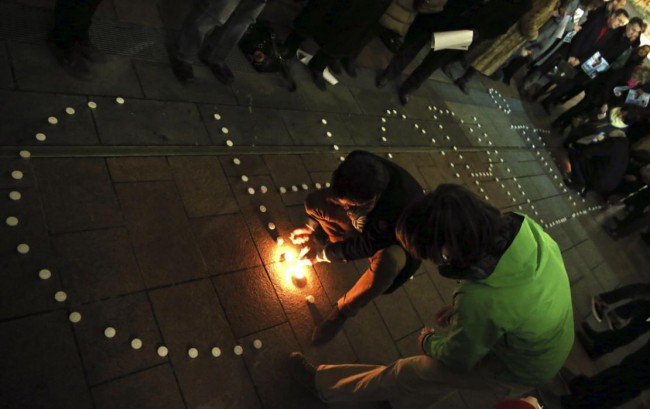 People try to light candles to form the word "Charlie" to pay tribute to the victims of a shooting by gunmen at the offices of weekly satirical magazine Charlie Hebdo in Paris, in front of the EU Parliament in Brussels