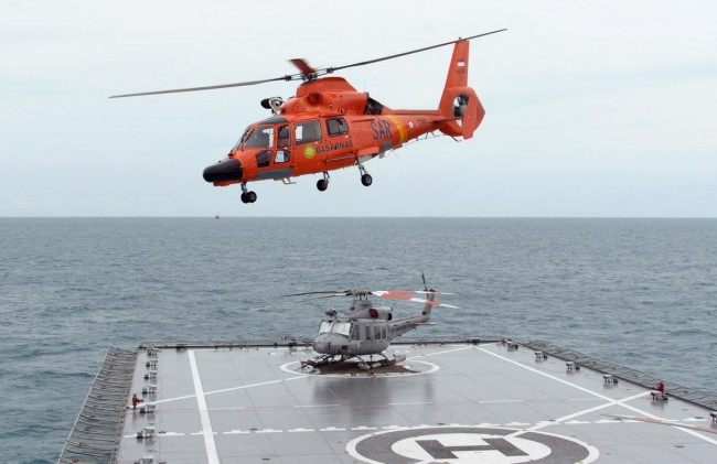 A national search and rescue helicopter departs from Indonesian navy vessel KRI Banda Aceh, transporting a dead body close to an area where the team found the tail of AirAsia QZ8501 in the Java sea