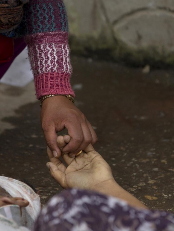 A Nepalese woman holds the hand of her relative killed in an earthquake at a hospital, in Kathmandu, Nepal, Sunday, April 26, 2015. A strong magnitude 7.8 earthquake shook Nepal's capital and the densely populated Kathmandu Valley before noon Saturday, causing extensive damage with toppled walls and collapsed buildings, officials said(AP Photo/Manish Swarup)