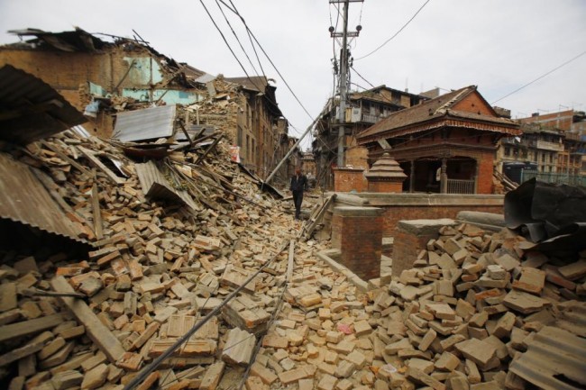 A Nepalese man walks through destruction caused by Saturday's earthquake, in Bhaktapur, Nepal, Sunday, April 26, 2015. A powerful, magnitude 6.7 aftershock shook the Kathmandu area of Nepal on Sunday, a day after the massive earthquake devastated the region and destroyed homes and infrastructure. (AP Photo/Niranjan Shrestha)