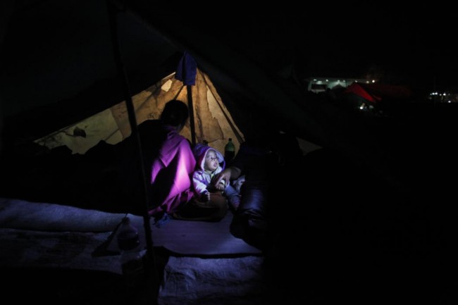 A Nepalese woman sits inside in a tent with her child as people stay on open ground from fears of earthquake tremors in Kathmandu, Nepal, Monday, April 27, 2015. A strong magnitude earthquake shook Nepals capital and the densely populated Kathmandu valley on Saturday devastating the region and leaving tens of thousands shell-shocked and sleeping in streets. (AP Photo/Niranjan Shrestha)