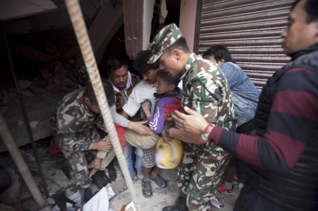 Volunteers carry an injured boy after rescuing him from the debris of a building that was damaged in an earthquake in Kathmandu, Nepal, Saturday, April 25, 2015. A strong magnitude-7.9 earthquake shook Nepal's capital and the densely populated Kathmandu Valley before noon Saturday, causing extensive damage with toppled walls and collapsed buildings, officials said. (AP Photo/ Niranjan Shrestha)