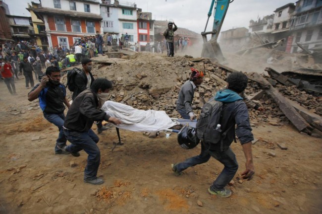 Volunteers carry the body of a victim on a stretcher, recovered from the debris of a building that collapsed after an earthquake  in Kathmandu, Nepal, Saturday, April 25, 2015. A strong magnitude-7.9 earthquake shook Nepal's capital and the densely populated Kathmandu Valley before noon Saturday, causing extensive damage with toppled walls and collapsed buildings, officials said. (AP Photo/ Niranjan Shrestha)