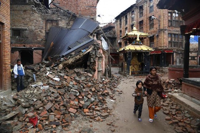 In this Thursday, April 30, 2015, photo, a Nepalese woman and a child walk near the rubble of collapsed buildings at Bhaktapur Durbar Square, a UNESCO World Heritage Site, on the outskirts of Kathmandu, Nepal. Kit Miyamoto, the structural engineer touring Kathmandu, called the damage in the capital, and the possibility that aftershocks could cause much more, a wakeup call. The government and outside nations should begin work to strengthen existing buildings and construct stronger new ones. (AP Photo/Manish Swarup)