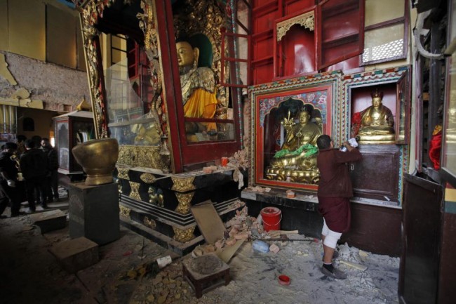 In this Thursday, April 30, 2015 photo, a man looks at a Buddhist God statue inside a monastery near the famous Swayambhunath stupa after it was damaged in the April 25 massive earthquake in Kathmandu, Nepal. Swayambhunath, which dates back to the 5th century, is one of at least 68 cultural heritage sites in Nepal that were damaged by the earthquake. (AP Photo/Niranjan Shrestha)