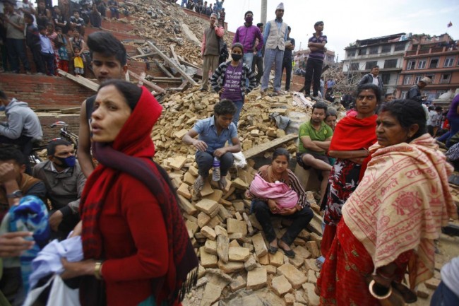 People rest on debris at Durbar Square after an earthquake in Kathmandu, Nepal, Saturday, April 25, 2015. A strong magnitude-7.9 earthquake shook Nepal's capital and the densely populated Kathmandu Valley before noon Saturday, causing extensive damage with toppled walls and collapsed buildings, officials said. (AP Photo/ Niranjan Shrestha)