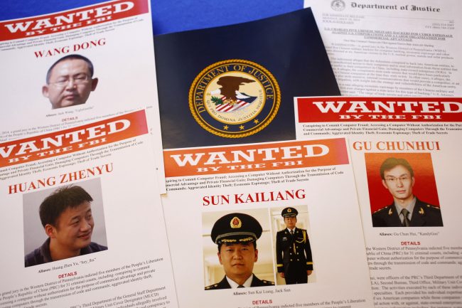FILE - This May 19, 2014 file photo shows press material displayed at the Justice Department in Washington before a press conference by U.S. Attorney General Eric Holder to announce charges of economic espionage and trade secret theft against five Chinese military officers, all hackers in an international cyber-espionage case. In the two weeks since the Obama administration accused them of hacking into American companies to steal trade secrets, the Chinese officers have yet to be placed on Interpols public listing of international fugitives, and there is no evidence that China would even entertain a formal request by the U.S. to extradite them. (AP Photo/Charles Dharapak, File)